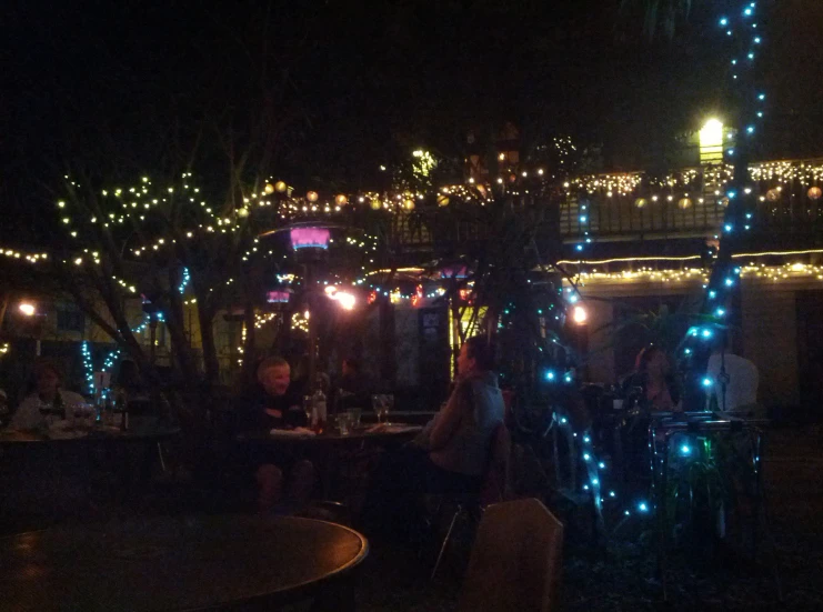 several people sitting around tables covered in lights