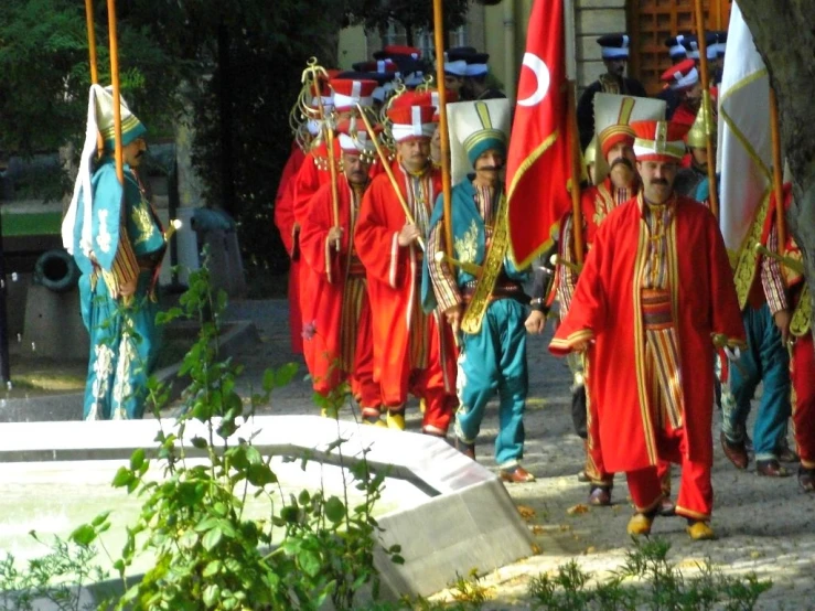 s in traditional costumes lead a parade through a park