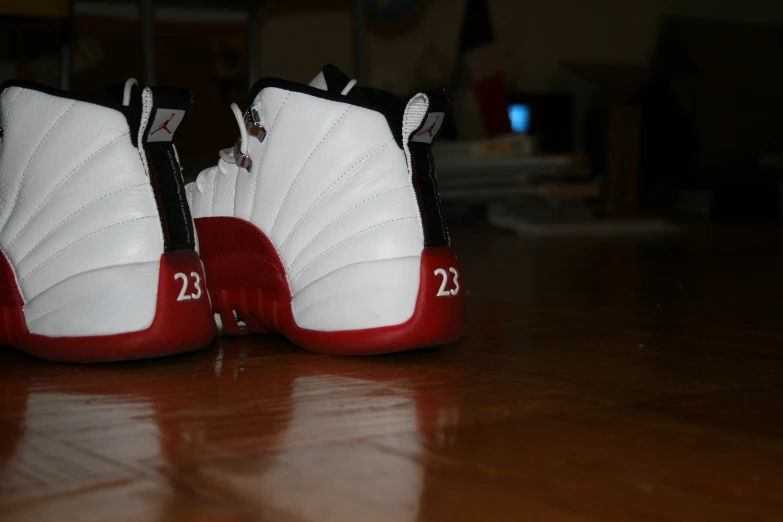 two pairs of red and white shoes on a wooden surface