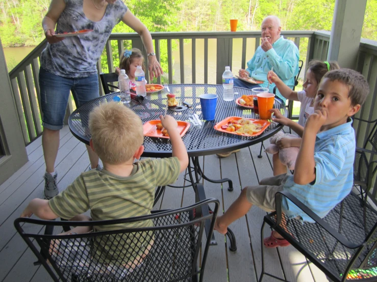 a group of s sit around a table outside