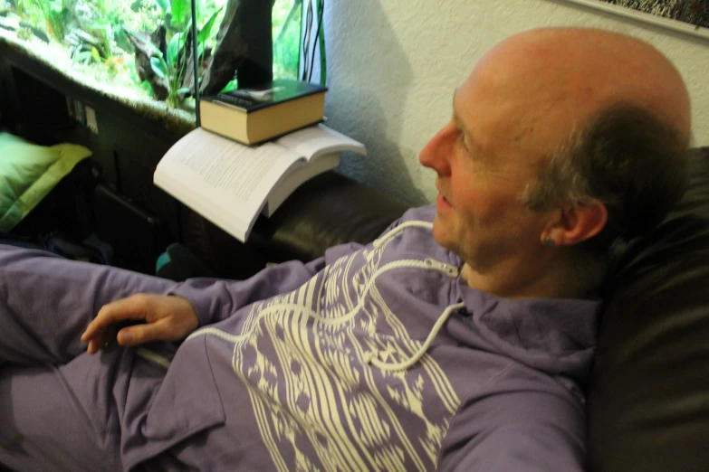 man wearing purple shirt looking at aquarium in corner