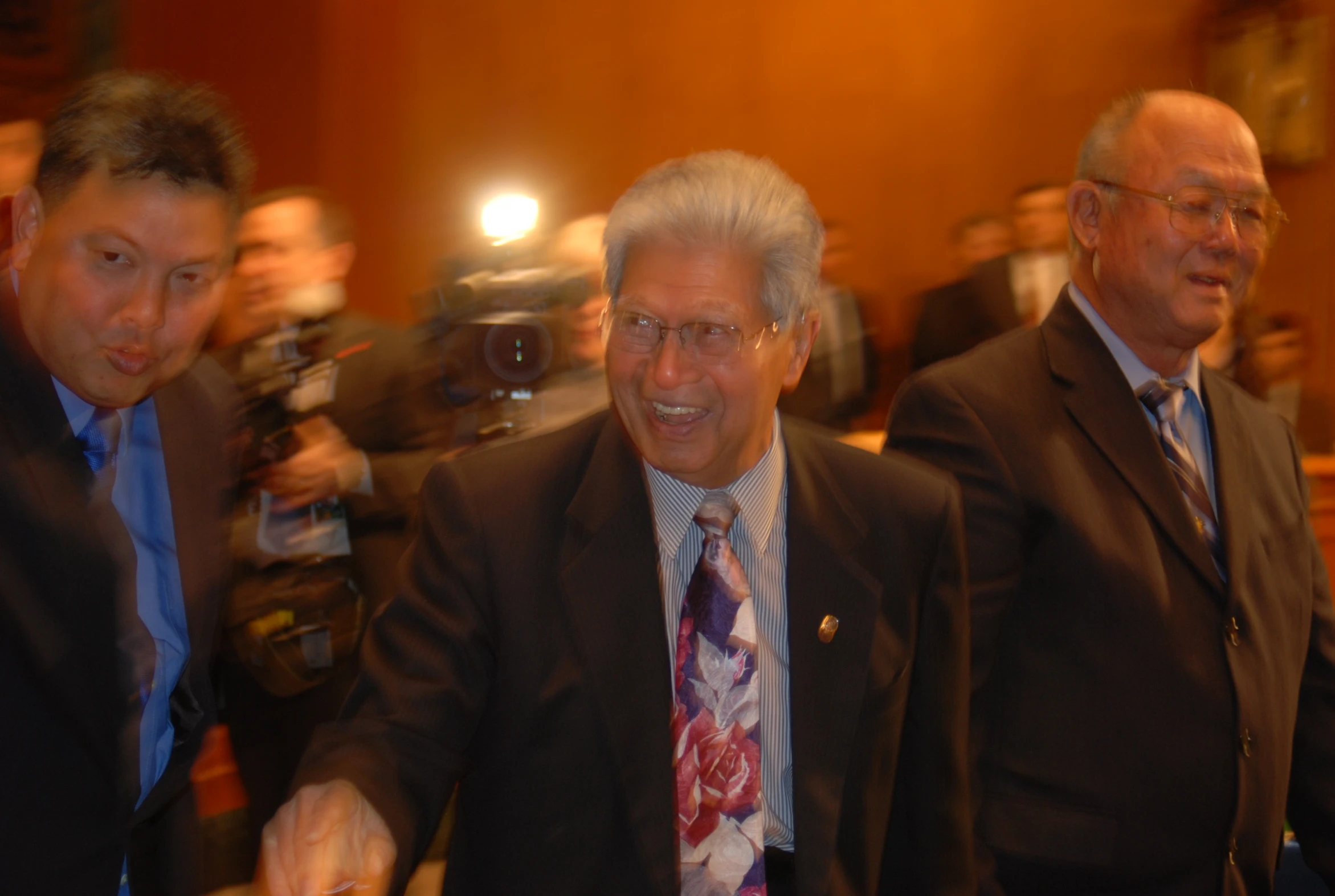 two men walk in front of a group of reporters