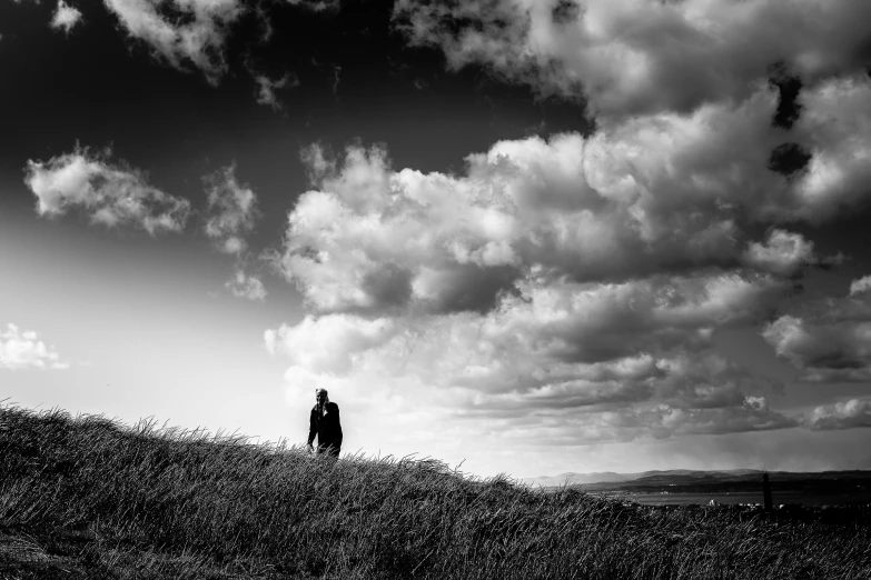 a person walking up a hill toward some clouds