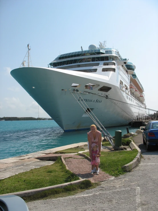 a woman walking on a sidewalk near a large cruise ship