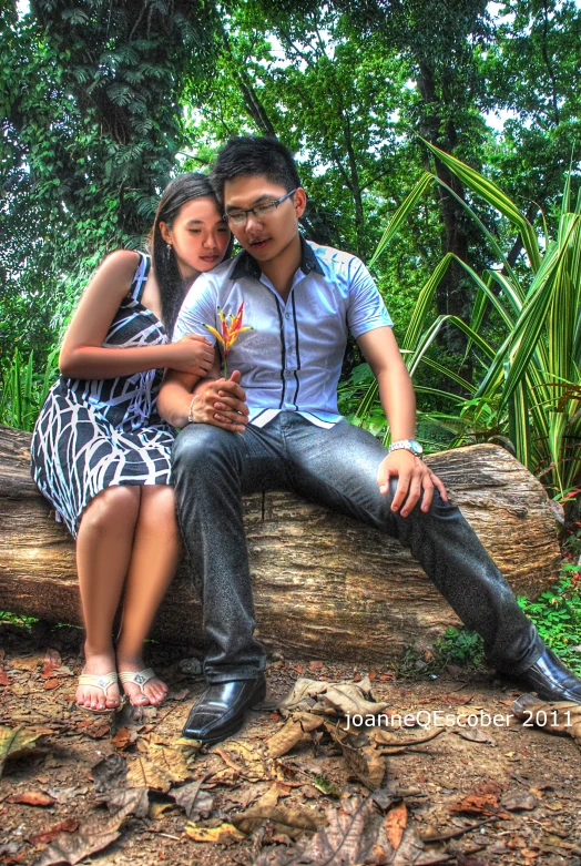 a man and woman on a tree log posing for a picture