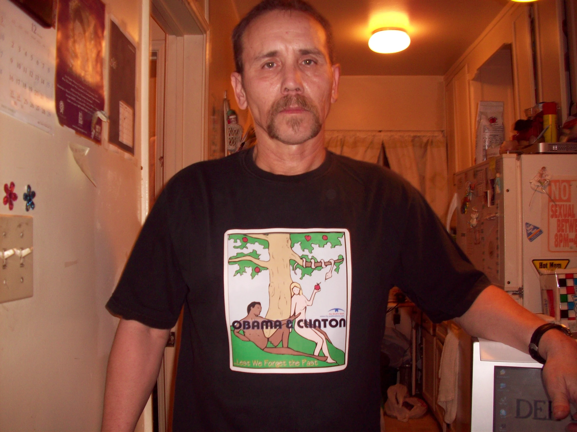 a man is posing in a hallway with a tree t - shirt on