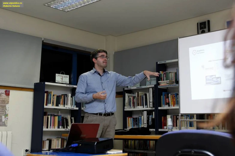 a man in a blue and white shirt standing next to books