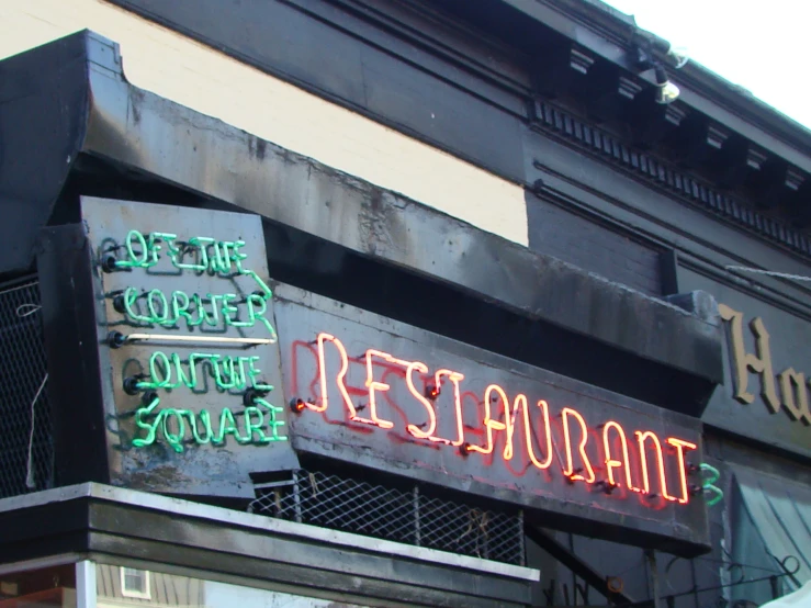 a neon sign is mounted to a side of a restaurant