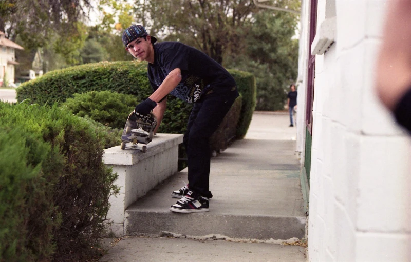 there is a male skateboarder in action on the sidewalk