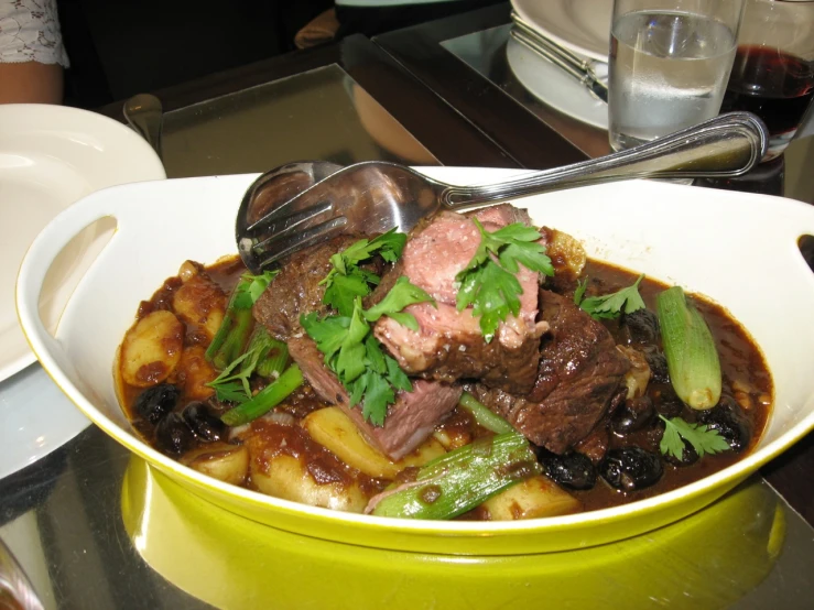 a bowl with meat and vegetables in it on a table