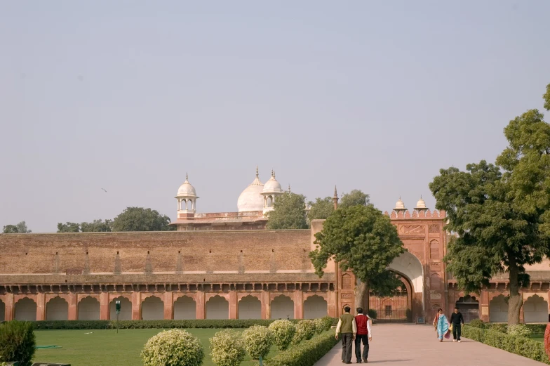 a group of people walking in front of a large brick building