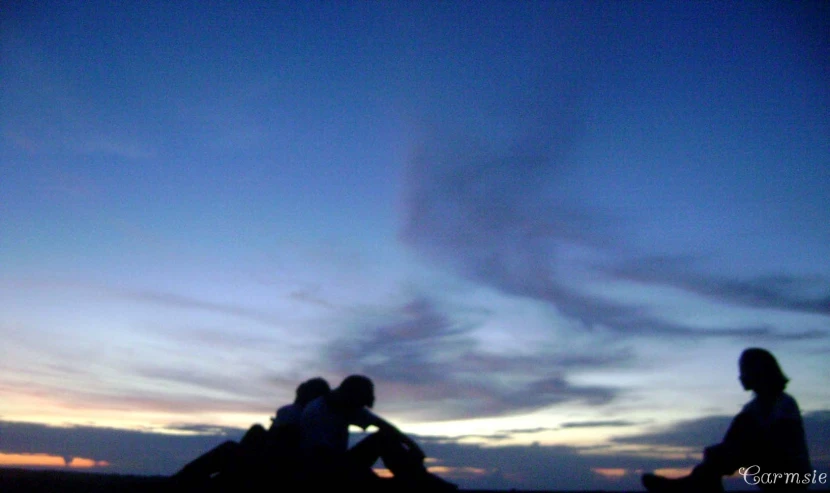 three people watching the sky from a grassy area