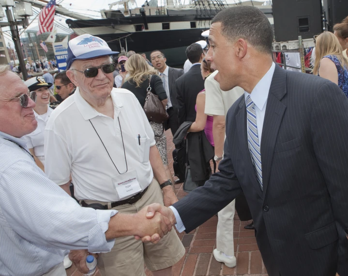 two men shake hands while others look on