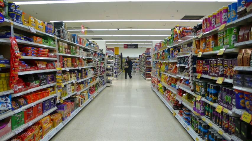 people shopping in a grocery store aisle full of products