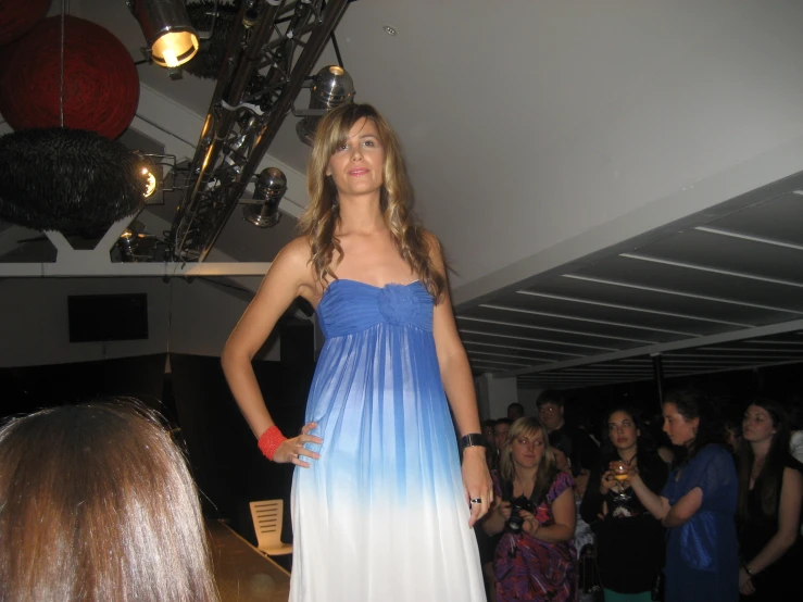 a woman posing in a strapless dress at a runway show
