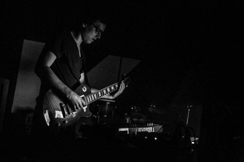 a person playing guitar while standing in the dark