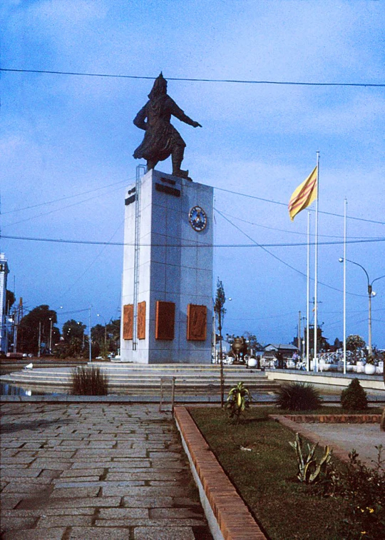 the statue is outside near a building and flags