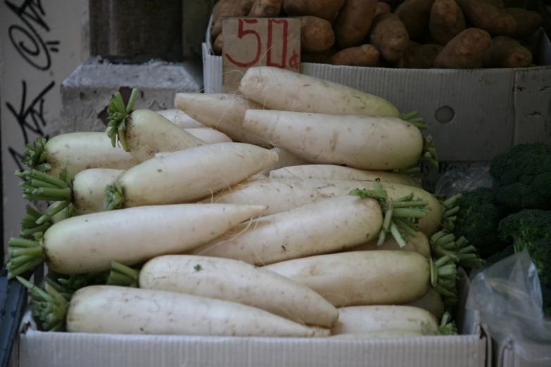 a crate of turnips with other veggies in it