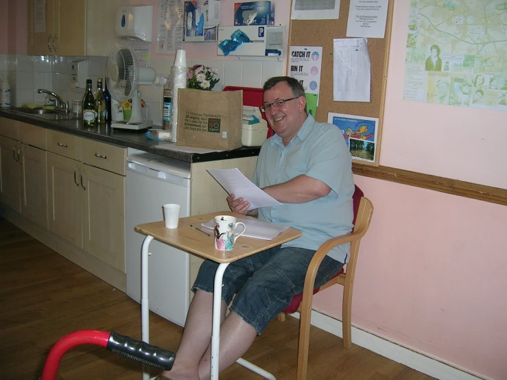 a man sitting at his kitchen table reading a piece of paper