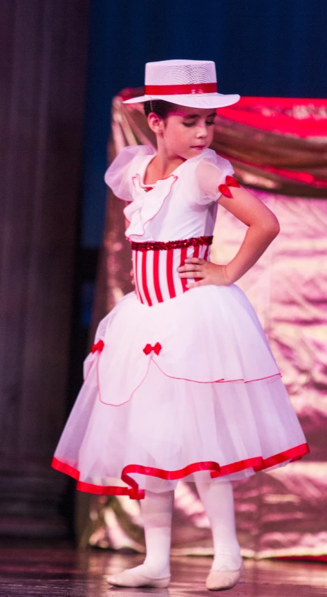 a little girl in a red and white dress with matching hat