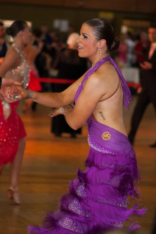 two ladies in purple outfits dance on a dance floor