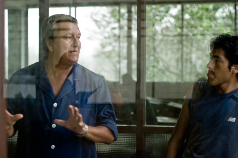 man talking to another man while in a mirrored reflection