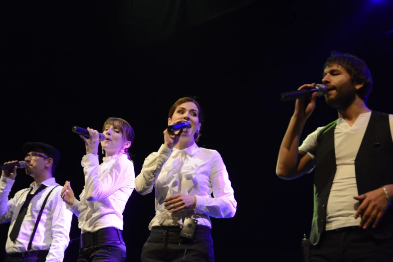 a group of people on stage singing into microphones