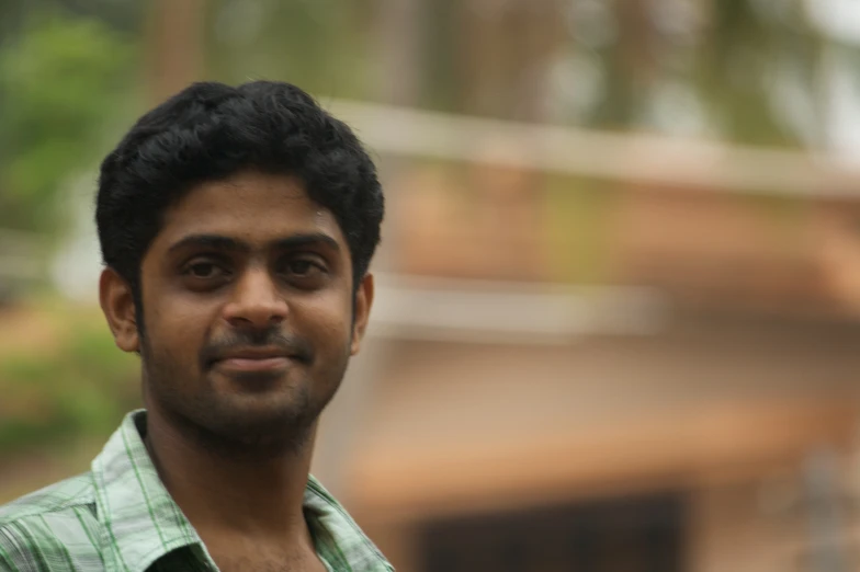 a man in checkered shirt smiling while standing