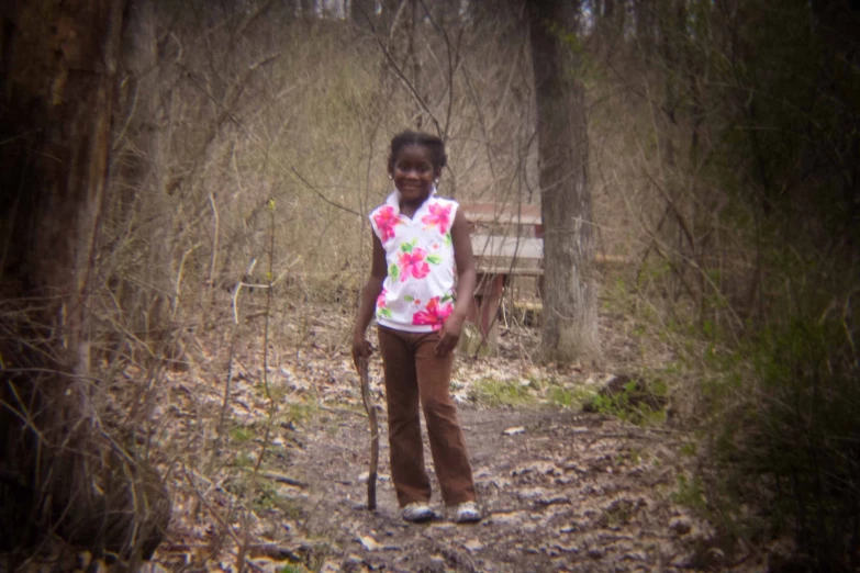 girl with long pants walking up dirt trail in the woods