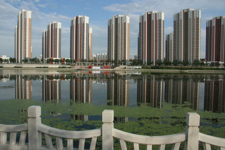 a few benches are in front of a water surface and the reflection is from other buildings