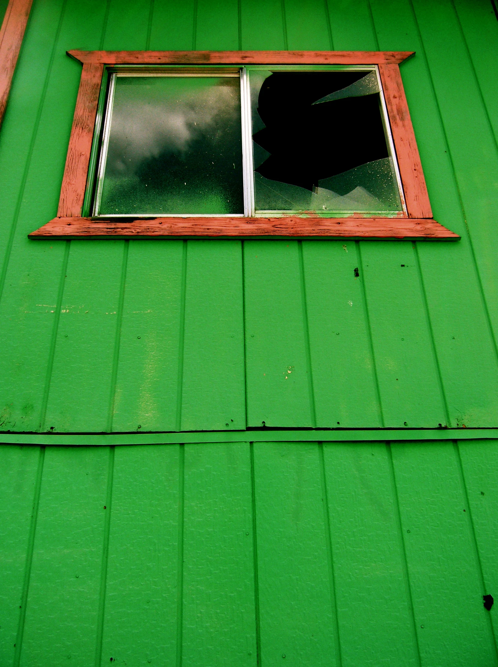 a green, tin - clad building with an open window
