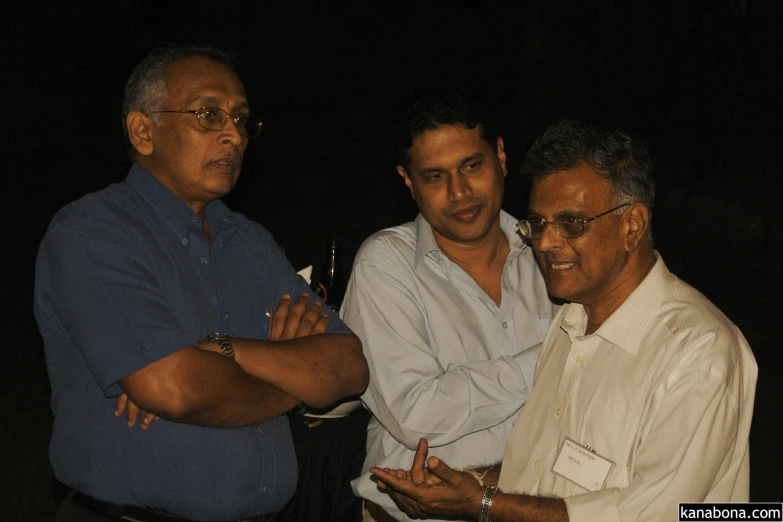 two men with arms crossed are talking to another man