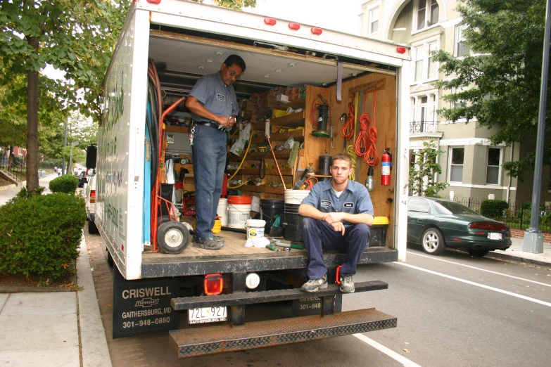 two men are standing outside a moving truck