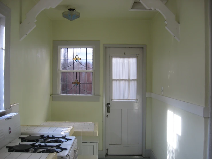 an empty kitchen has a white stove and two windows
