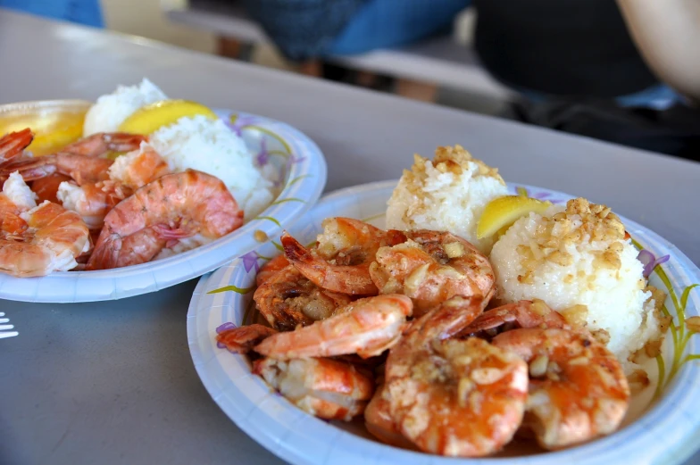 two plates with shrimp and crab on them sitting on a counter