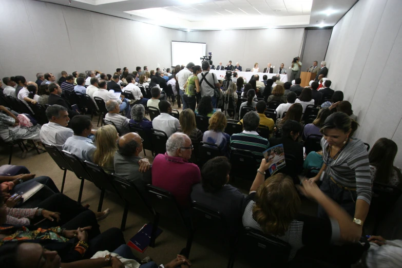 a crowd of people is sitting in chairs talking