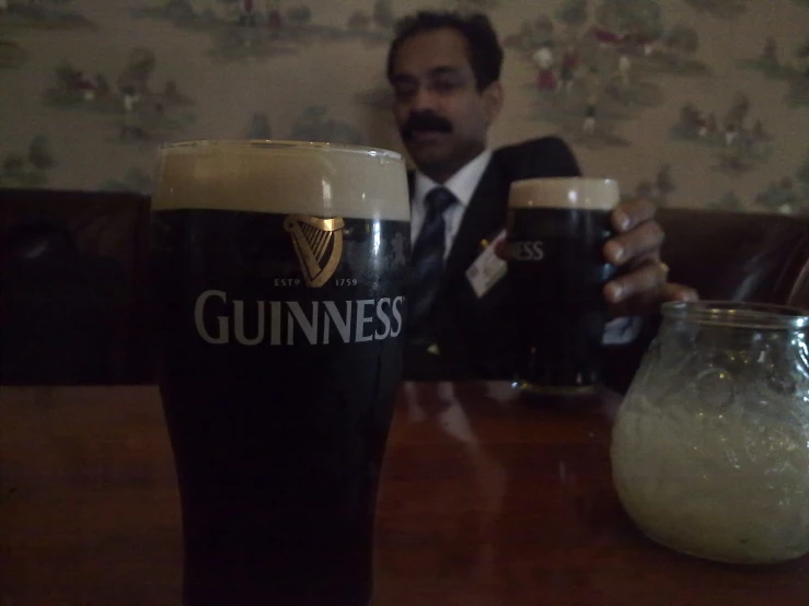 a man in a suit is sitting with two beers