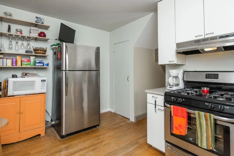 an open kitchen with a silver refrigerator and oven