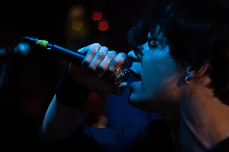 a man holding a microphone in his mouth and singing into it