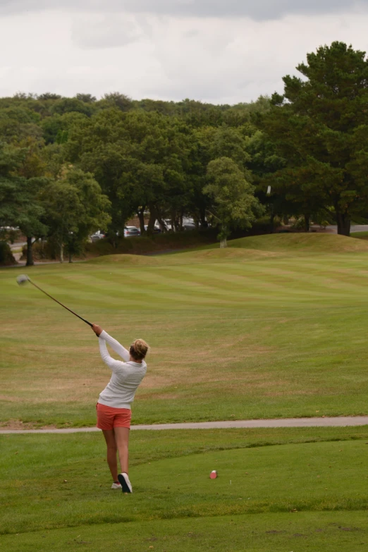 a woman swinging her golf club at a golf ball