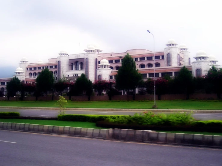 a building behind a road next to a lush green park