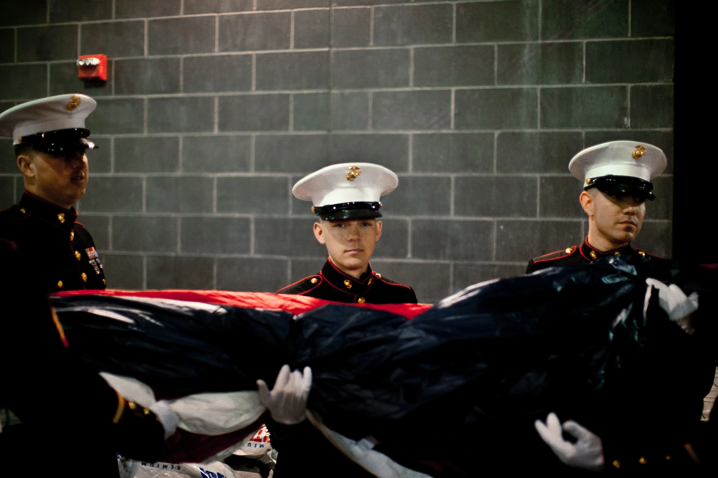 a couple of men holding an american flag next to a wall