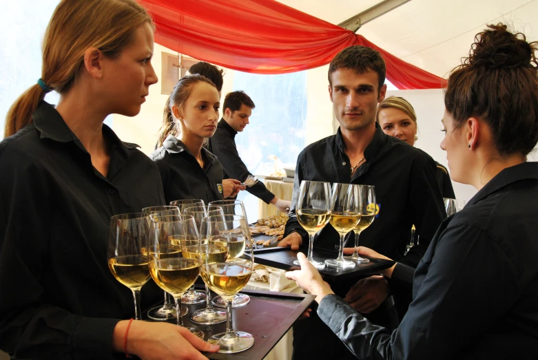 several people standing around drinking glasses of wine