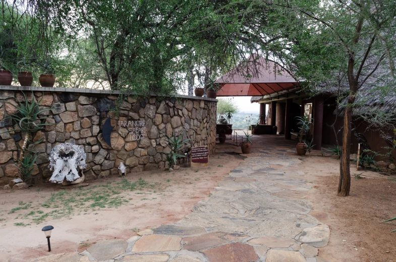 the stone wall and brick pathway is lined with pots