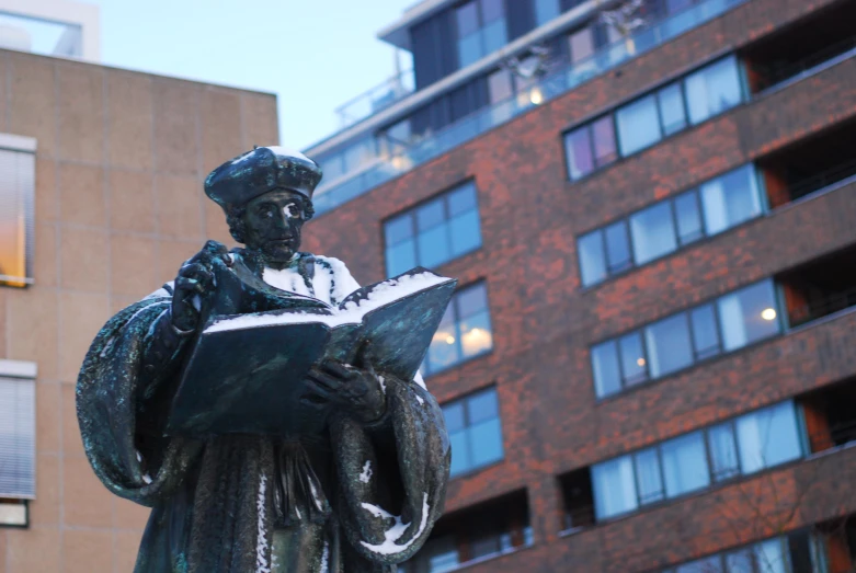 a statue of a man in a uniform holding a book next to a building