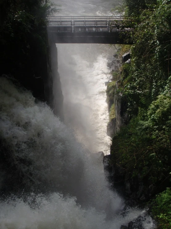 the water is flowing under a bridge near rocks