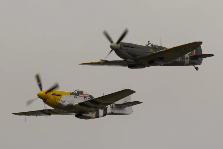 two fighter planes flying in the air with propellers