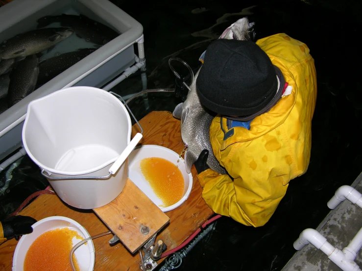 a man sitting next to two bowls of orange liquid