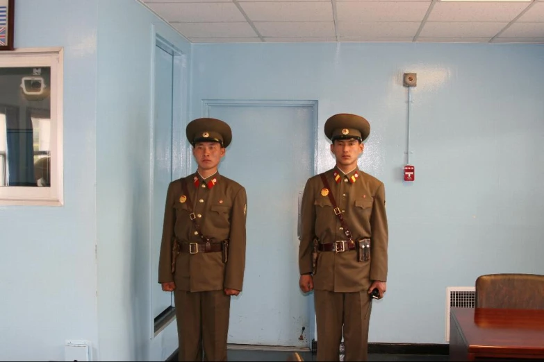 two military men are standing in uniforms in a room