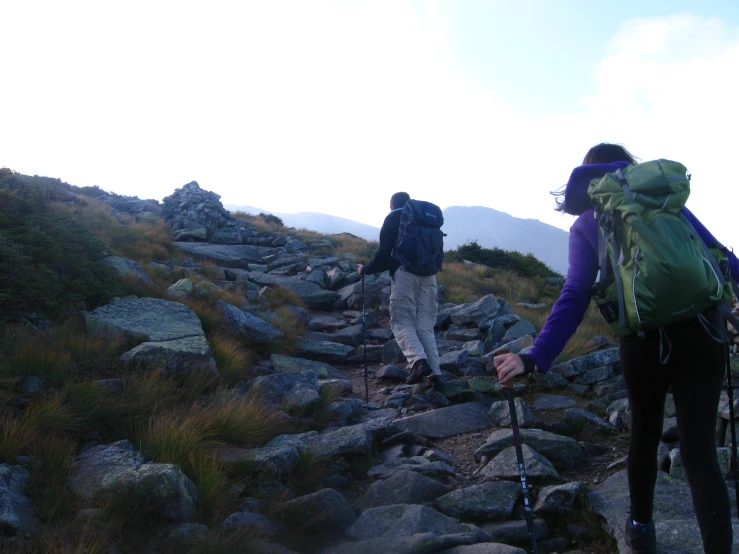 two people climbing up the side of a mountain